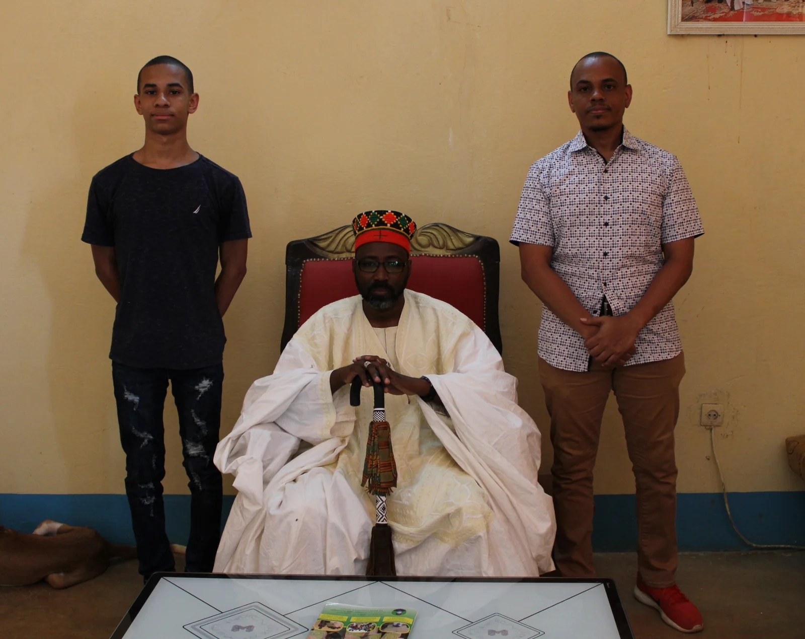 Visitors standing beside the seated King of Boussouma.